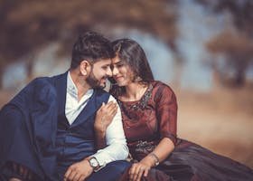 A loving couple sharing a tender moment outdoors, highlighting their romantic connection and stylish attire.