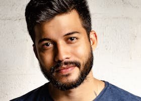 Close-up portrait of a handsome man with a beard in casual attire, smiling warmly.